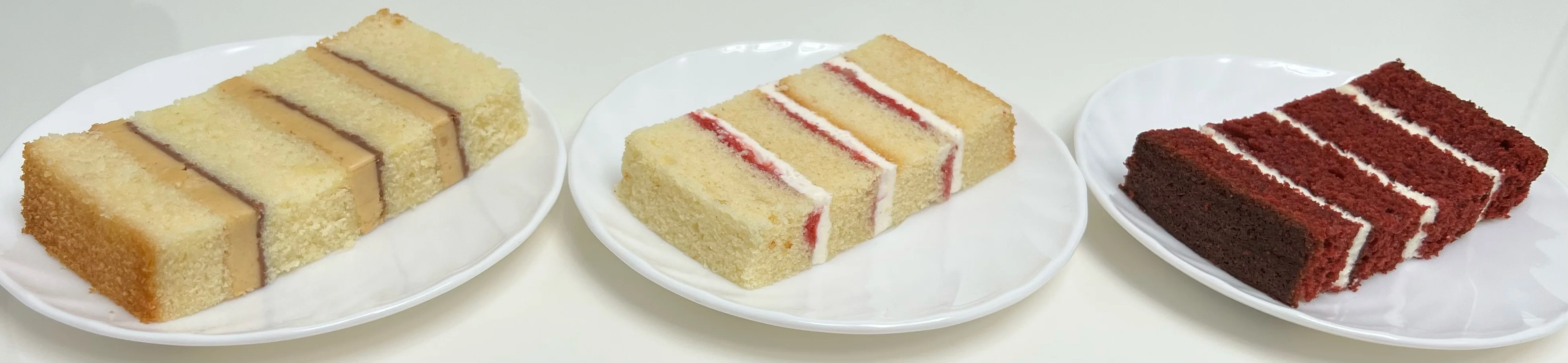 Three individual slices of different flavoured cake in a horizontal line