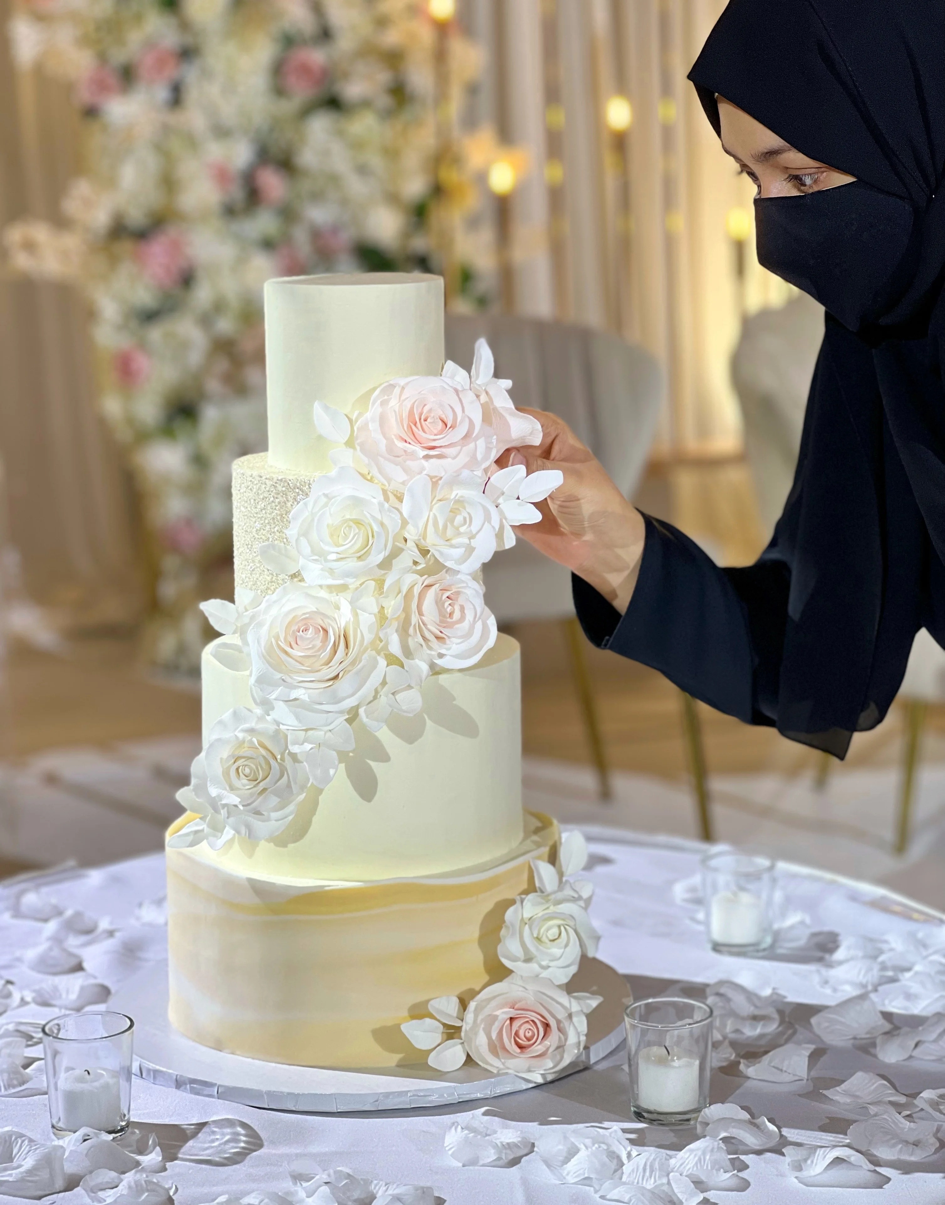 Blissful Crumbs cake designer assembling 4 tier wedding cake with handmade roses