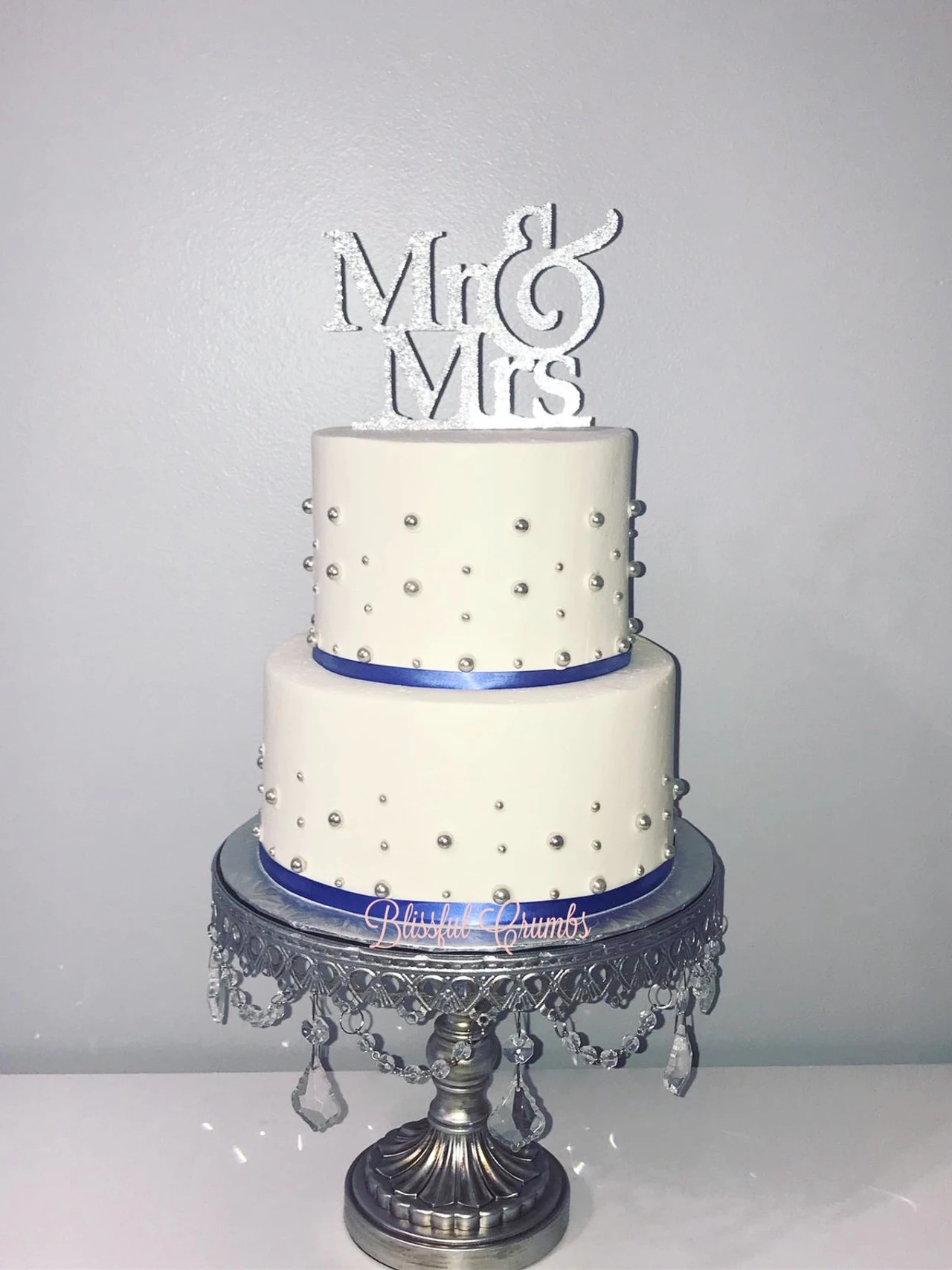 White cake with Mr & Mrs topper on a silver cake stand